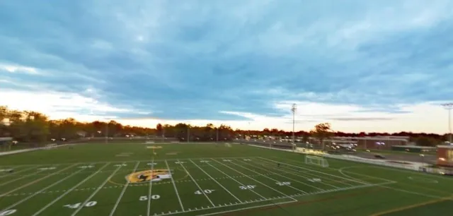 An athletic field and stands photographed from above at dusk