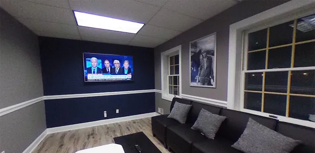 An office lounge with seating and a wall-mounted screen
